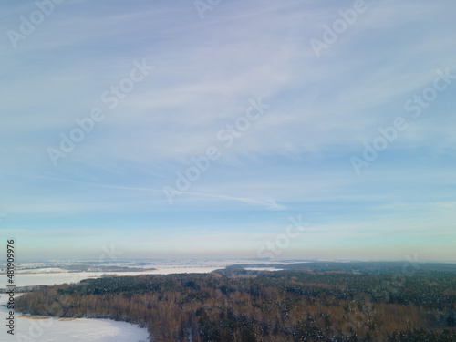 White snow, blue and gray sky,  forest and field. Top view on a winter snowy day. © Tatiana