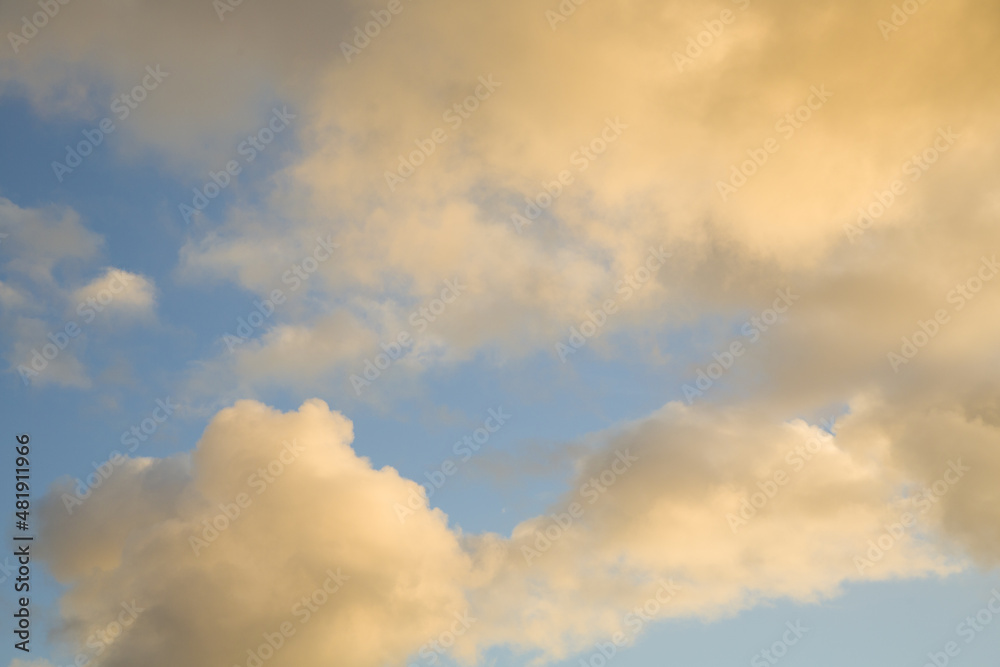 Blue sky with orange clouds illuminated by the evening sunset sun.