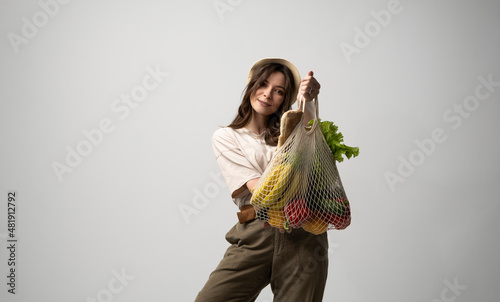 Young brunette woman bought a eco foods in zero waste shop and put it in amesh eco bag. Zero waste. Ecologically and environmentally friendly packets. Vegan Lifestyle Concept. photo