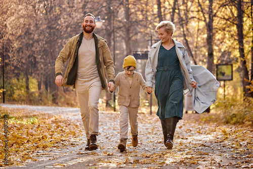 Excited caucasian family running, having fun in the park, autumn season, sunny day. cheerful positive spend vactions holidays on fresh air, smiling and laughing. family, children, love, emotions photo