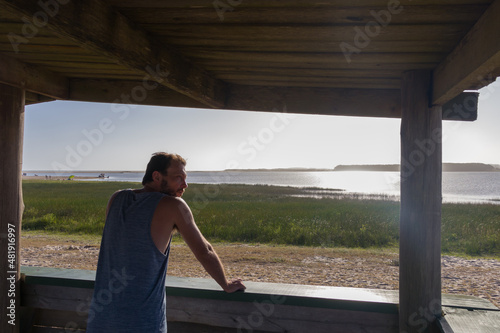 Hombre blanco joven solitario en un mirador frente a un lago.