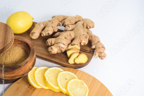 Fresh ginger root, lemon on white marble table
