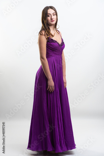 Full body portrait of gorgeous young brunette woman dressed in exquisite nude ball gown with lace top. Attractive female model in elegant strapless dress posing against white background.