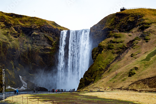 Skogafoss in Iceland with blue skies and green hills