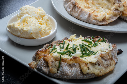 Traditional Finnish foods - Fresh Karelian pies with rice pudding filling and egg butter and chives topping against black background.