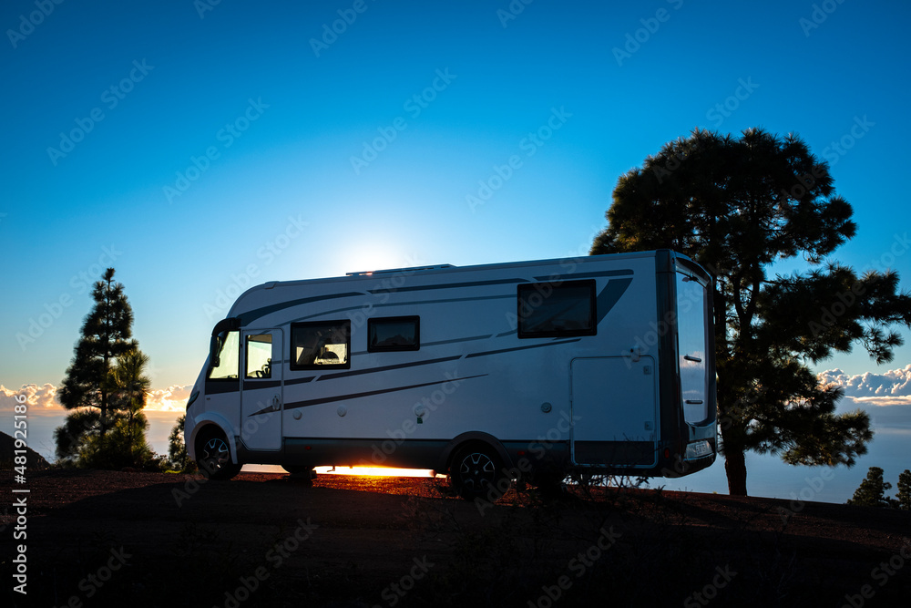 Camper van parked against sunset light and trees. Concept of alternative lifestyle vanlife and travel wanderlust. Summer holiday vacation with camping car recreational vehicle