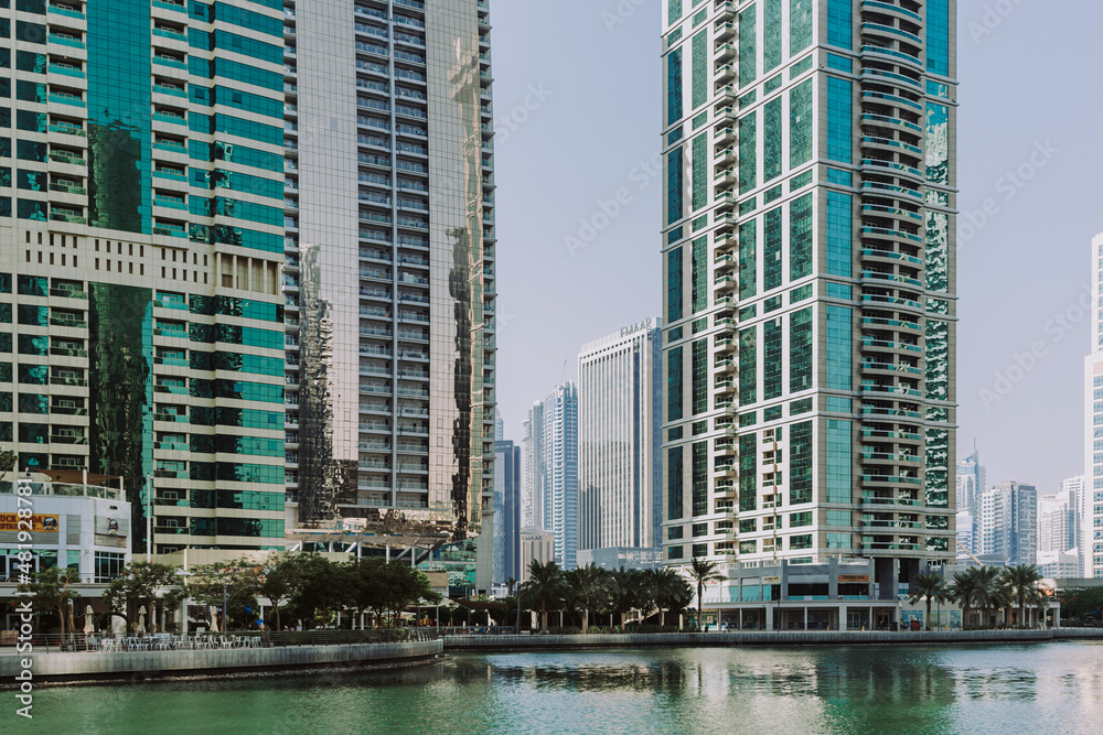 Obraz premium Modern city skyscrapers buildings at sunset time with business and residential towers around the lake and palm trees