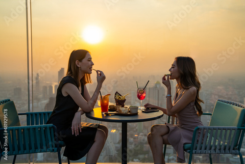 Beautiful Asian woman friends meeting and dinner party together at skyscraper rooftop restaurant in metropolis at summer sunset. Female friend enjoy outdoor lifestyle activity in the city at night © CandyRetriever 