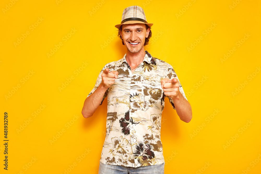 Fototapeta premium studio portrait of a joyful smiling male traveler tourist, holding his index fingers in front of him. shows the forward direction with both hands. concept - people, vacation abroad, weekend, tour