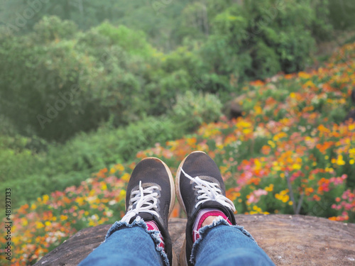 Selfie hipster wearing sneaker shoes over flower field background on mountain.