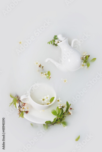 White teapot and tea cups with cherry flowers , leaves