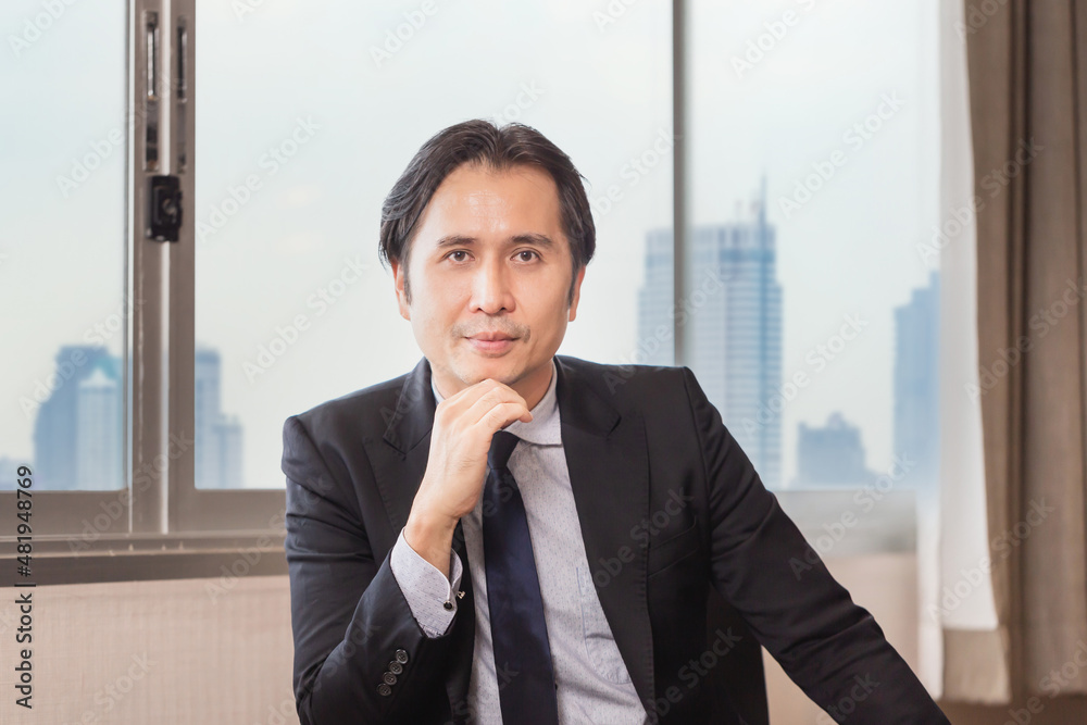 Smiling business man sitting at office desk and looking at camera Smiling business man sitting at office desk and looking at camera