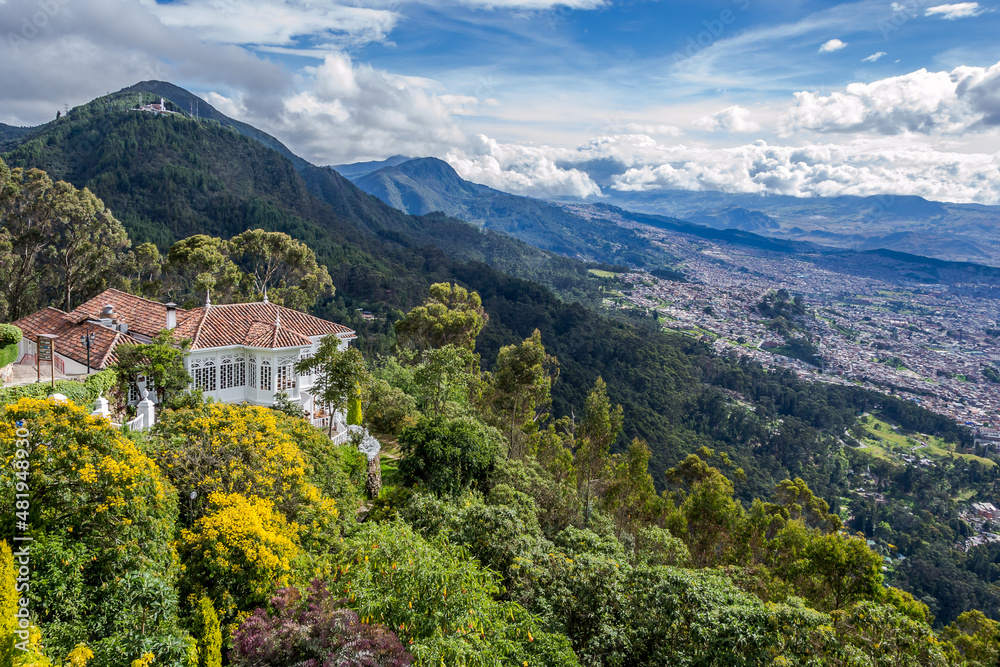 Fototapeta premium View of Monserrate, a high Mountain dominating the city center of Bogota - capital of Colombia, - major tourist attraction and pilgrim destination in a beautiful cloudy day