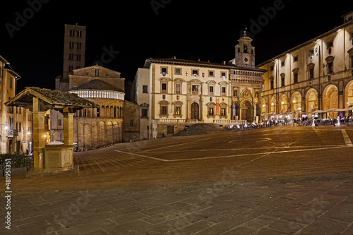 Arezzo, Tuscany, Italy: night view of the main square Piazza Grande, with the medieval church and buildings, in the old town of the ancient Italian city of art