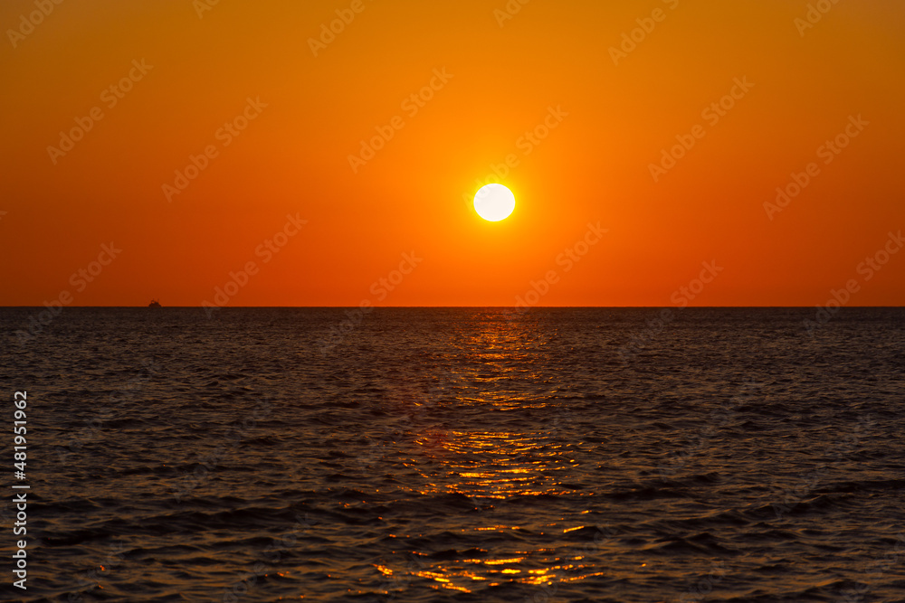 Sunset sea boat. Romantic summer landscape with a round orange sun. Minimalism in nature. The concept of summer, recreation, tourism, travel on a sea ship. tropical sunset or sunrise over the ocean