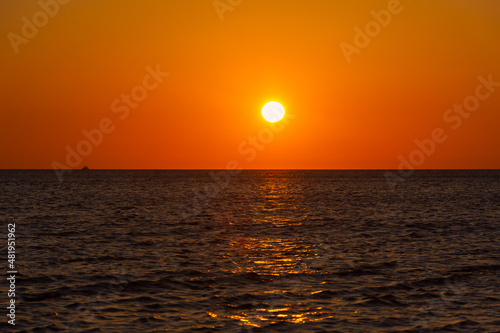 Sunset sea boat. Romantic summer landscape with a round orange sun. Minimalism in nature. The concept of summer  recreation  tourism  travel on a sea ship. tropical sunset or sunrise over the ocean