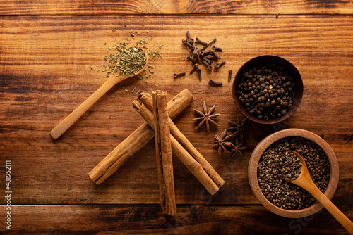 Selection of various spices on wooden rustic board background. Pepper, cardamom, clove, cinnamon, star anis, dehydrated parsley..Flat lay