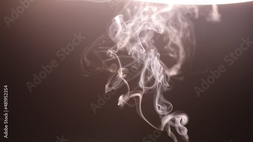 Burning charcoal and incense sticks smoke on dark background.
