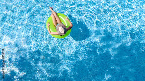 Active young girl in swimming pool aerial top view from above  child relaxes and swims on inflatable ring donut and has fun in water on family vacation  tropical holiday resort
