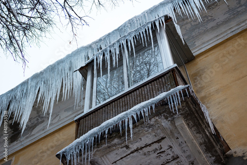 Large sharp icicles cover the roof and balcony at an apartment building