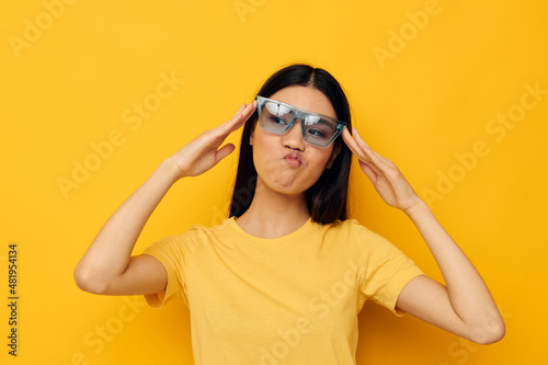 cheerful woman in yellow t-shirt and stylish glasses posing fashion