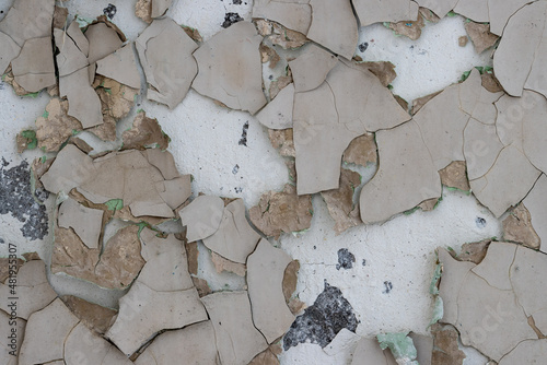Fototapeta Naklejka Na Ścianę i Meble -  Peeling paint on the wall. Old concrete wall with cracked flaking paint. Weathered rough painted surface with patterns of cracks and peeling. Grunge texture for background and design. High resolution.