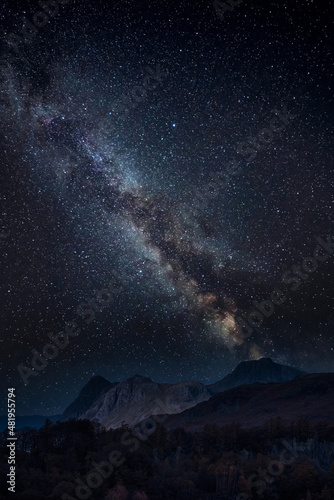 Digital composite image of Milky Way and stunning landscape image of stunning Langdale Pikes looking from Holme Fell in Lake District