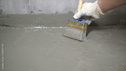 The process of applying mortar - waterproofing to a concrete floor. The concept of waterproofing the floor with a brush. photo