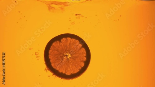 Orange in a glass of juice. Slow motion