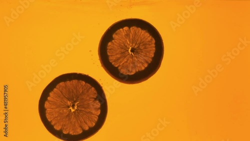 Orange in a glass of juice. Slow motion