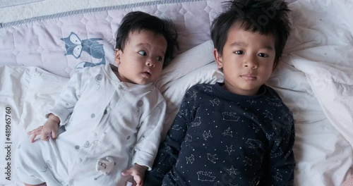 Happy brother and sisiter baby playing  together on bed in cozy house photo