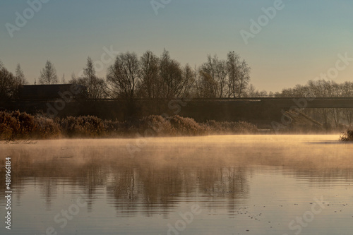 big truck runs over bridge in cold misty autumn morning, reflection of trees and grass, transport bridge. Golden sunrise light in fog