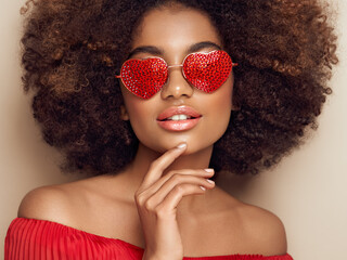 Beautiful portrait of an African girl in sunglasses in the shape of hearts. Valentine's Day. Symbol of love