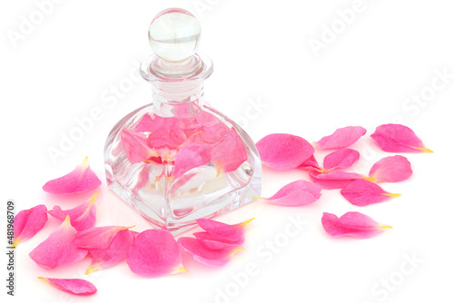 Rose water in an art deco glass bottle and pink petals. Can help maintain skin pH balance, is anti bacterial, helps to reduce redness of skin, can help heal acne, dermatitis and eczema. On white. photo