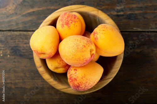 Fresh apricots in a wooden plate.