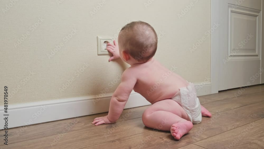 Baby toddler reaches into the electrical outlet on the home wall with his hand. Danger and protection of child fingers from electric shock Baby toddler reaches into the electrical outlet on the home wall with his hand. Danger and protection of child fingers from electric shock