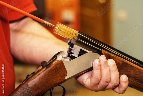 The process of cleaning a shotgun with a plastic brush. Caring for firearms with special tools. Close-up. Unrecognizable person photo