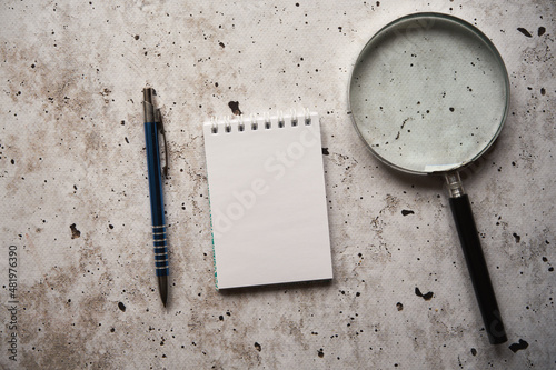 notes, lupa i długopis na betonowym stole