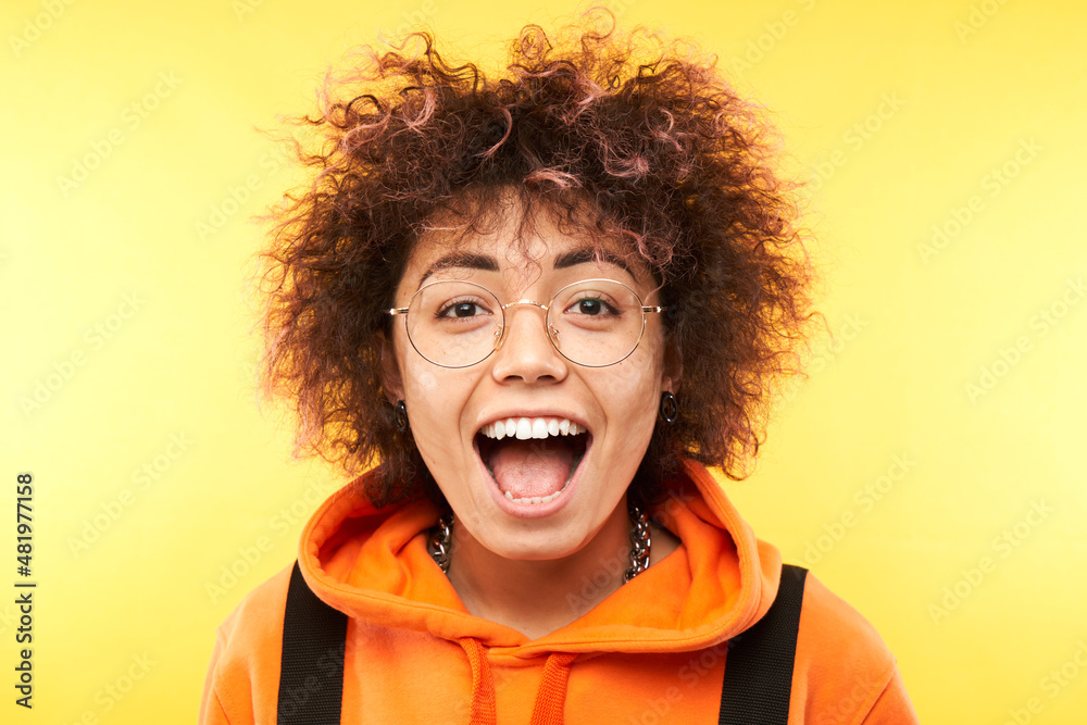 Shocked kazakh girl face with afro curls and tourist backpack looks surprised close-up on white studio background Shocked kazakh girl face with afro curls and tourist backpack looks surprised close-up on white studio background