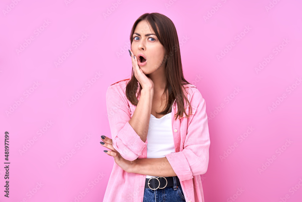 Shocked brunette girl looking surprised with open mouth on pink background with copy space Shocked brunette girl looking surprised with open mouth on pink background with copy space