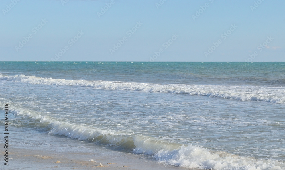 Sea waves roll over one another, forming white foam.Visible horizon line