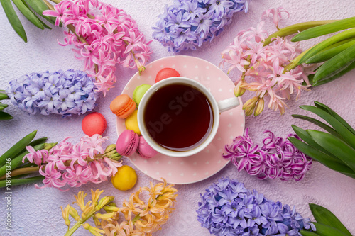 Cup of tea with colorful macaroons and hyacinths, top view.