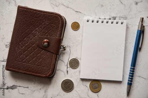 notes , długopis ,brązowy portfel i monety na marmurowym stole ,polski złoty 