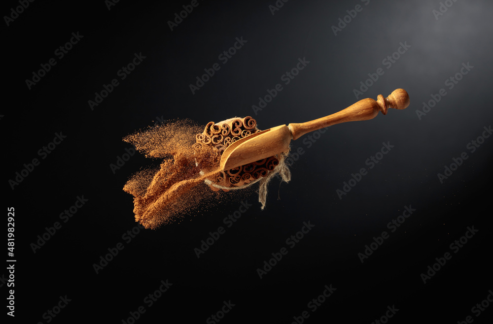 Fototapeta premium Cinnamon powder is poured out of the wooden spoon.