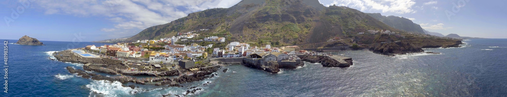Aerial panoramic view of Santiago del Teide landscape with homes and pools in Tenerife from drone.