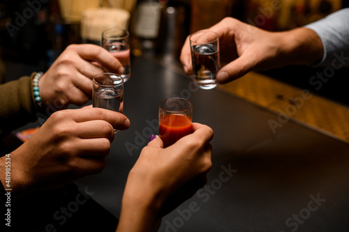 Male hands cheer with glasses of vodka and liqueur