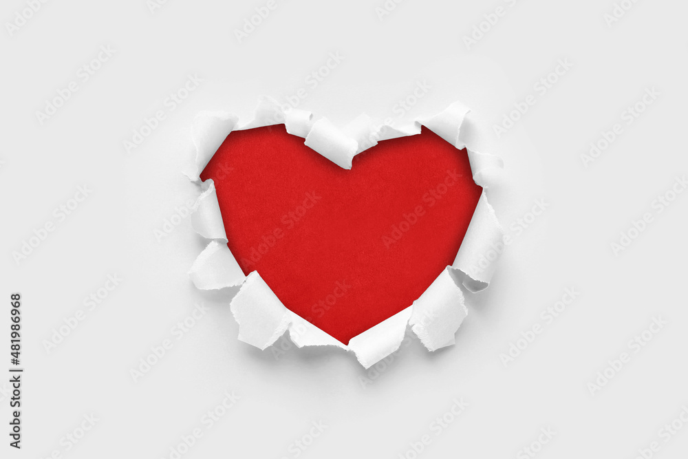 A paper hole with torn edges on a white background. Through paper. A ragged hole in the shape of a heart. Valentine's day. A symbol of love, romantic relationships. International Women's Day.