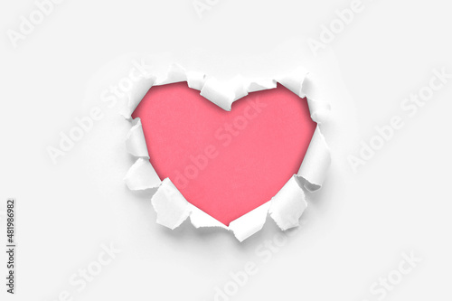 A paper hole with torn edges on a white background. Through paper. A ragged hole in the shape of a heart. Valentine's day. A symbol of love, romantic relationships. International Women's Day.