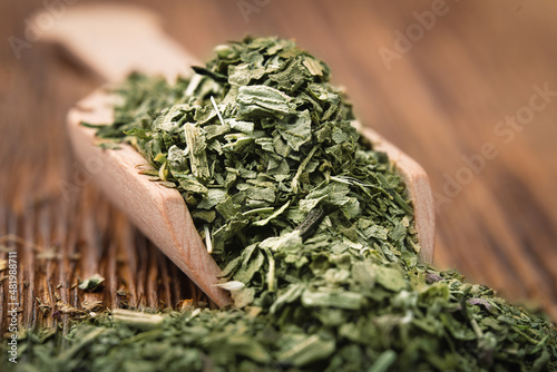 Crushed dried basil leaves in a wooden scoop Fototapet