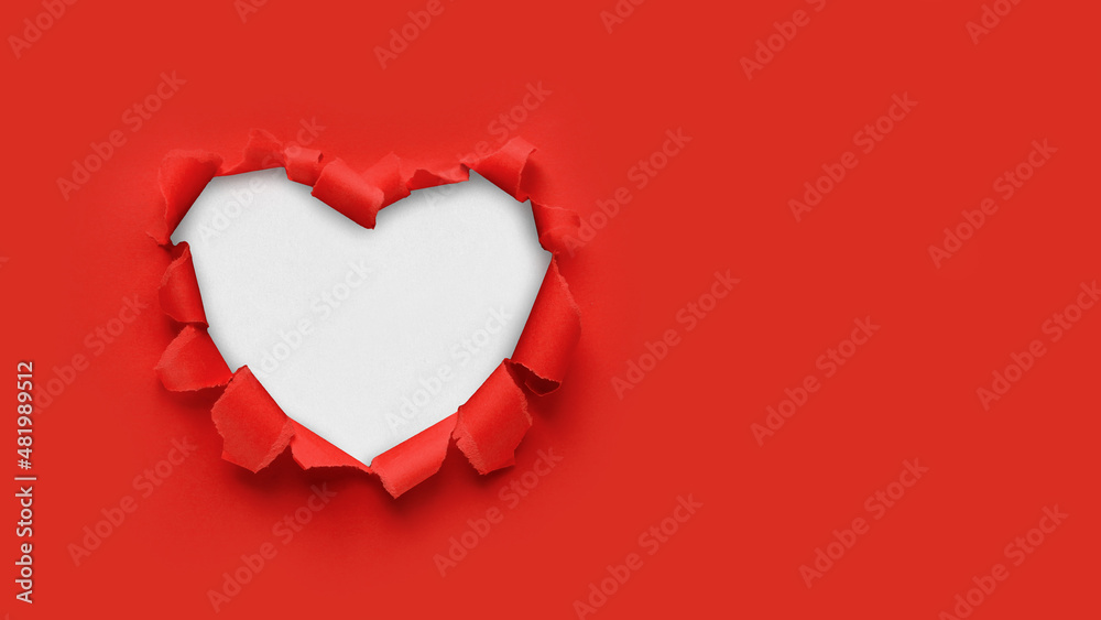 A paper hole with torn edges on a red background. Through paper. A ragged hole in the shape of a heart. Valentine's day. A symbol of love, romantic relationships. International Women's Day. A paper hole with torn edges on a red background. Through paper. A ragged hole in the shape of a heart. Valentine's day. A symbol of love, romantic relationships. International Women's Day.